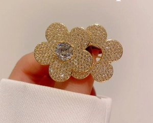 Detailed macro of golden double flower brooch with sparkling rhinestones held by hand