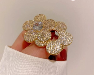 Detailed close-up of double flower brooch with micro-pave crystals and golden setting