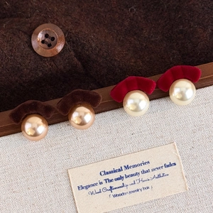 Detailed view of vintage pearl stud earrings with brown and wine red flocked fan shapes