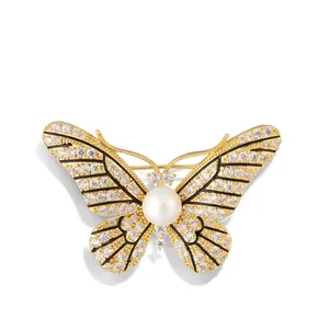 Elegant gold butterfly brooch with shimmering crystals and a large white round pearl center