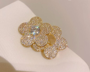 Detailed close-up of golden flower brooch with sparkling white zircons and center stone