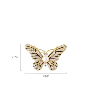 Elegant gold butterfly brooch with shimmering crystals and a large white pearl detail