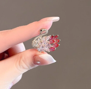 Macro detail of swan brooch with pink gradient crystals and gold plating on fingers