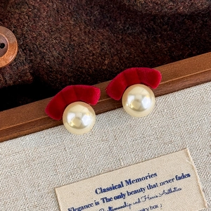 Detail of vintage red velvet fan studs with large faux pearls on a brown fabric background