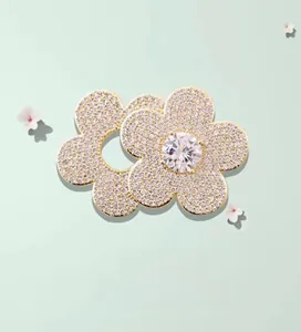 Detailed macro view of a gold flower brooch with sparkling cubic zirconia on green background