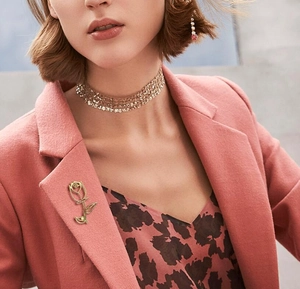 Detailed view of an elegant hollow rose brooch with central pearl on a pink blazer lapel