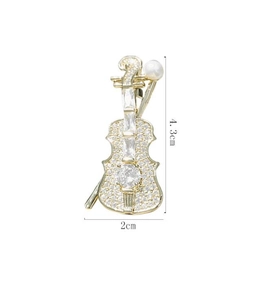 Detail view showing a 4.3cm gold violin brooch with rhinestones and white pearl
