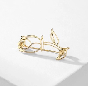 Detail shot of hollow rose brooch with elegant golden lines on a white pedestal