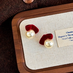 Detailed shot of vintage burgundy velvet bow earrings with cream pearl drop on wood