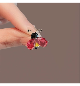 Vue macro de la broche abeille avec gemmes rouges poire et base dorée détaillée