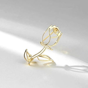 Macro detail of elegant hollow rose brooch in golden metal finish with sharp artistic shadows