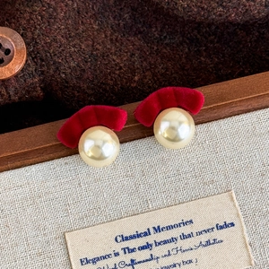 Detailed view of vintage earrings with red velvet accents and polished creamy pearls