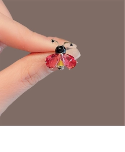 Détail d'une broche coccinelle avec ailes en pierres rouges et monture en métal doré