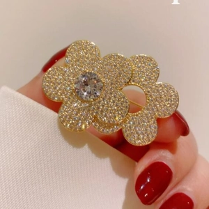 Elegant gold flower brooch with sparkling crystals and large zircon on a fabric background