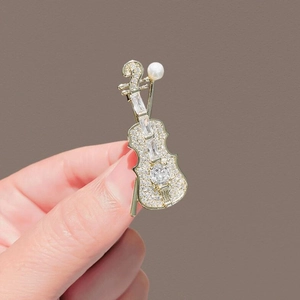 Detail of violin brooch featuring gold alloy, sparkling pavé crystals and a white pearl