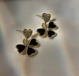 Detailed macro shot of vintage black floral earrings with gold edges and crystal center