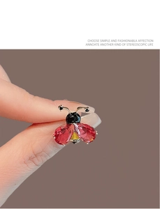 Gros plan d'une broche coccinelle en cristal rouge avec détails en métal doré