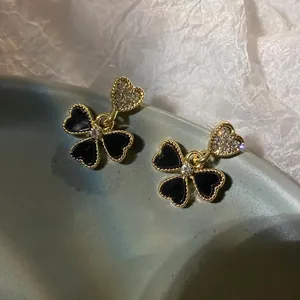 Detail of elegant heart-shaped gold studs with black floral resin charms and crystals
