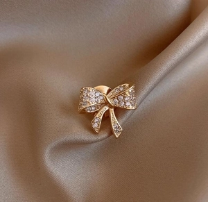 Macro di un'elegante spilla a fiocco dorata con micro-pavé di cristalli su seta