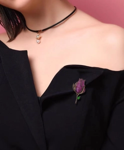 Detalle de un broche de rosa de cristal púrpura en la solapa de un blazer negro