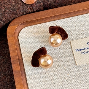 Detailed view of vintage flocked crescent earrings with elegant pearls on a wooden tray