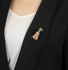 Detail of rose gold violin brooch with white crystals pinned on a black suit lapel