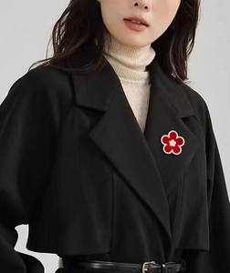 Detail of a red floral brooch with pearls on a black coat lapel in a vintage style
