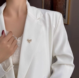 Spilla a fiocco con micro-cristalli su risvolto di abito bianco per stile elegante