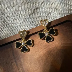 Detailed close-up of gold clover earrings with black onyx on a rustic wooden background