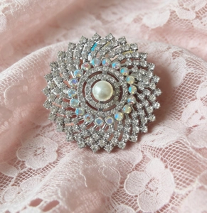 Macro shot of a luxury sunburst brooch with a central pearl and sparkling rhinestones