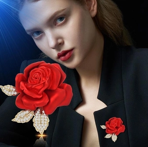 Broche rose rouge élégante avec feuilles dorées et cristaux sur un costume noir chic