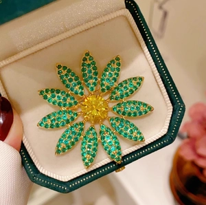 Macro detail of luxury floral brooch with yellow center stone and green pavé petals