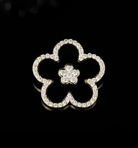 Macro detail showing black enamel five-petal flower brooch with white crystal trim decoration