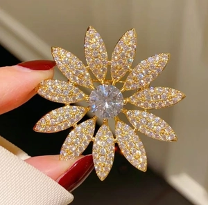 Luxury maple flower brooch in gold with white zircons held by hand to show actual size