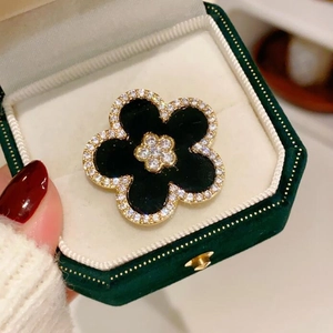 Elegant five-petal flower brooch with black inlay and crystals in a green velvet box