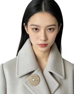 Detailed view of luxury sunflower brooch with pearl and crystals on grey wool coat