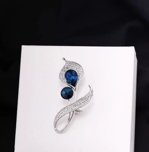 Détail d'une broche calla argentée avec cristal bleu profond et strass étincelants