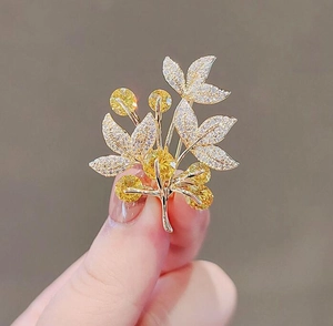Macro shot of a floral tree brooch with yellow gemstones and white crystals on gold