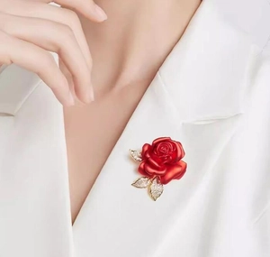 Détail de la broche rose rouge avec feuilles de cristal sur revers de costume blanc