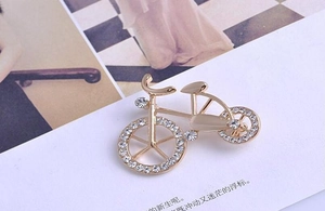 Close-up of a vintage bicycle brooch with white crystal rhinestones on a gold alloy frame