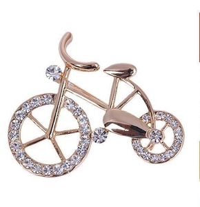 Detail shot of a rose gold vintage bicycle brooch with sparkling clear crystal rhinestones