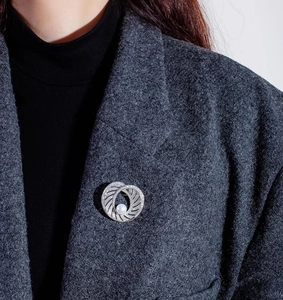Elegant pearl brooch with circular hollow design pinned on a grey wool blazer lapel