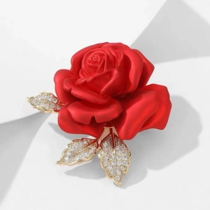 Broche élégante rose rouge avec feuilles dorées et cristaux sur fond blanc épuré