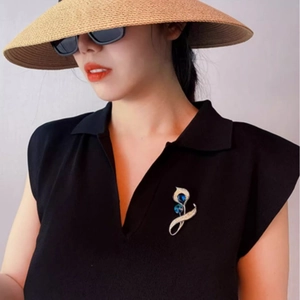 Élégante broche calla argentée avec cristaux bleus portée sur un pull noir à col en V