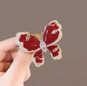 Detail of red enamel butterfly brooch with sparkling crystals and gold metallic plating