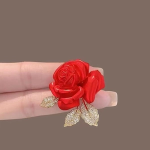 Broche de rose rouge élégante avec feuilles dorées et zircons à la main