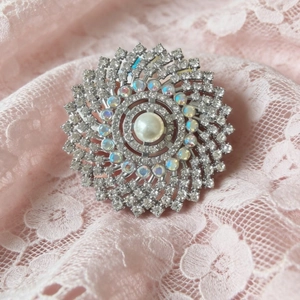 Elegant floral pearl brooch with radiating petals and AB crystals on pink lace background