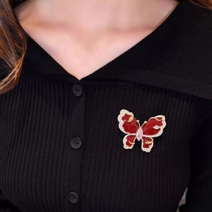 Elegant red butterfly brooch with sparkling crystals on black knitwear garment