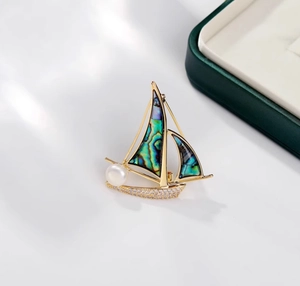 Détail d'une broche voilier avec nacre d'abalone, perle blanche et cristaux scintillants