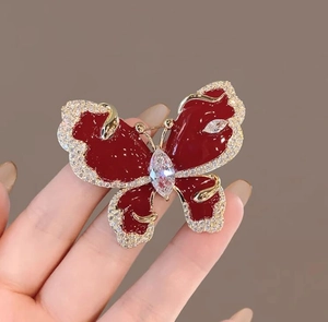 Close-up of butterfly brooch with red enamel wings and sparkling zircon inlay